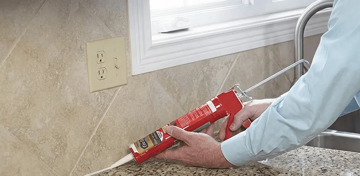 Handyman applying caulk along a kitchen backsplash and countertop seam in Arlington, TX