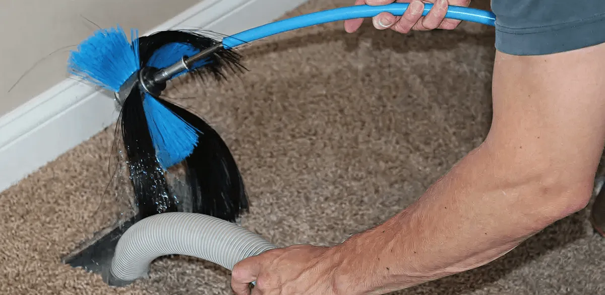 Dryer vent cleaning technician brushing lint from a vent line in Arlington, TX